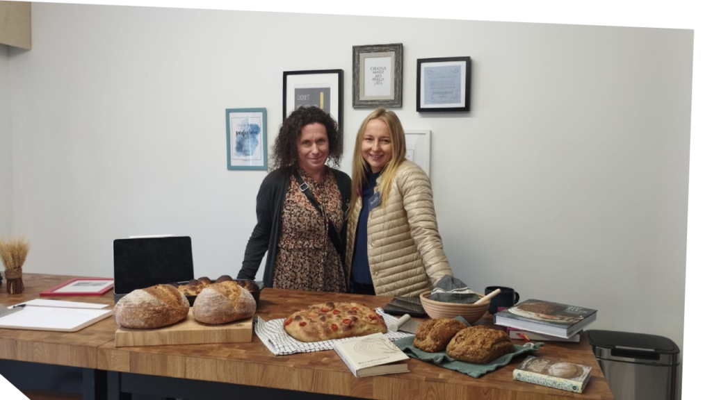 Two women stand behind a table full of freshly baked bread.